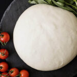 A ball of freshly made pizza dough from scratch, ready to be rolled out and topped for a delicious homemade pizza.