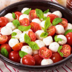 A vibrant Caprese Salad, highlighting fresh mozzarella, ripe tomatoes, and aromatic basil leaves - an embodiment of Italian simplicity and freshness.