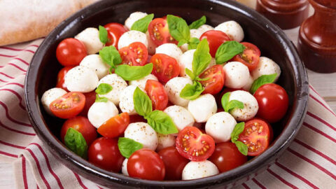 A vibrant Caprese Salad, highlighting fresh mozzarella, ripe tomatoes, and aromatic basil leaves - an embodiment of Italian simplicity and freshness.