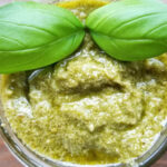 A vibrant bowl of Pesto alla Genovese topped with two whole basil leaves, silky and aromatic, a beloved Italian sauce with a multitude diverse uses.