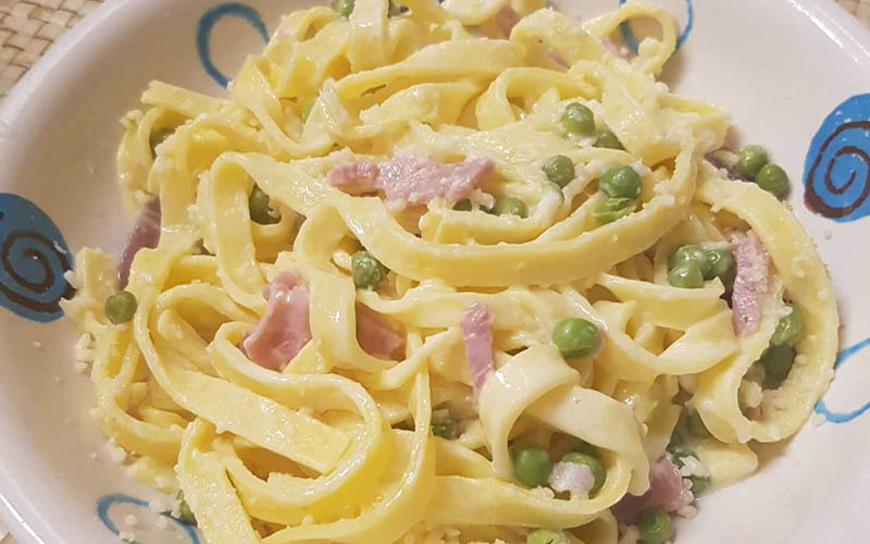 A delicious serving of Fettuccine Panna with Prosciutto Cotto and Peas, a renowned Italian dish.