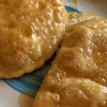 A serving of Sardinian Honey and Pecorino Seadas, showcasing the creamy cheese filling and gooey honey topping, an evolution from a main dish to a savory dessert.