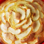A delicious slice of Apple Cake, dense and sweet with soft apple pieces. Plated in a contrasting red bowl and ready to be paired with a morning espresso.